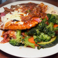 Chicken Sorrentino a chicken breast topped with eggplant, prosciutto, and fresh mozzarella with a red sauce, mashed potatoes and vegetables.