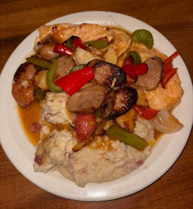 Plated dish with chicken, sausage, and vegetables on a white plate.