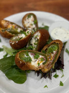 Bread rolls stuffed with a creamy filling and garnished with herbs on a white plate.