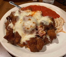 A plate of Shrimp Parmigiana with melted cheese on top, served with pasta and marinara sauce.
