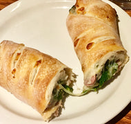 A broccoli rabe sausage roll cut in half, served on a plate.